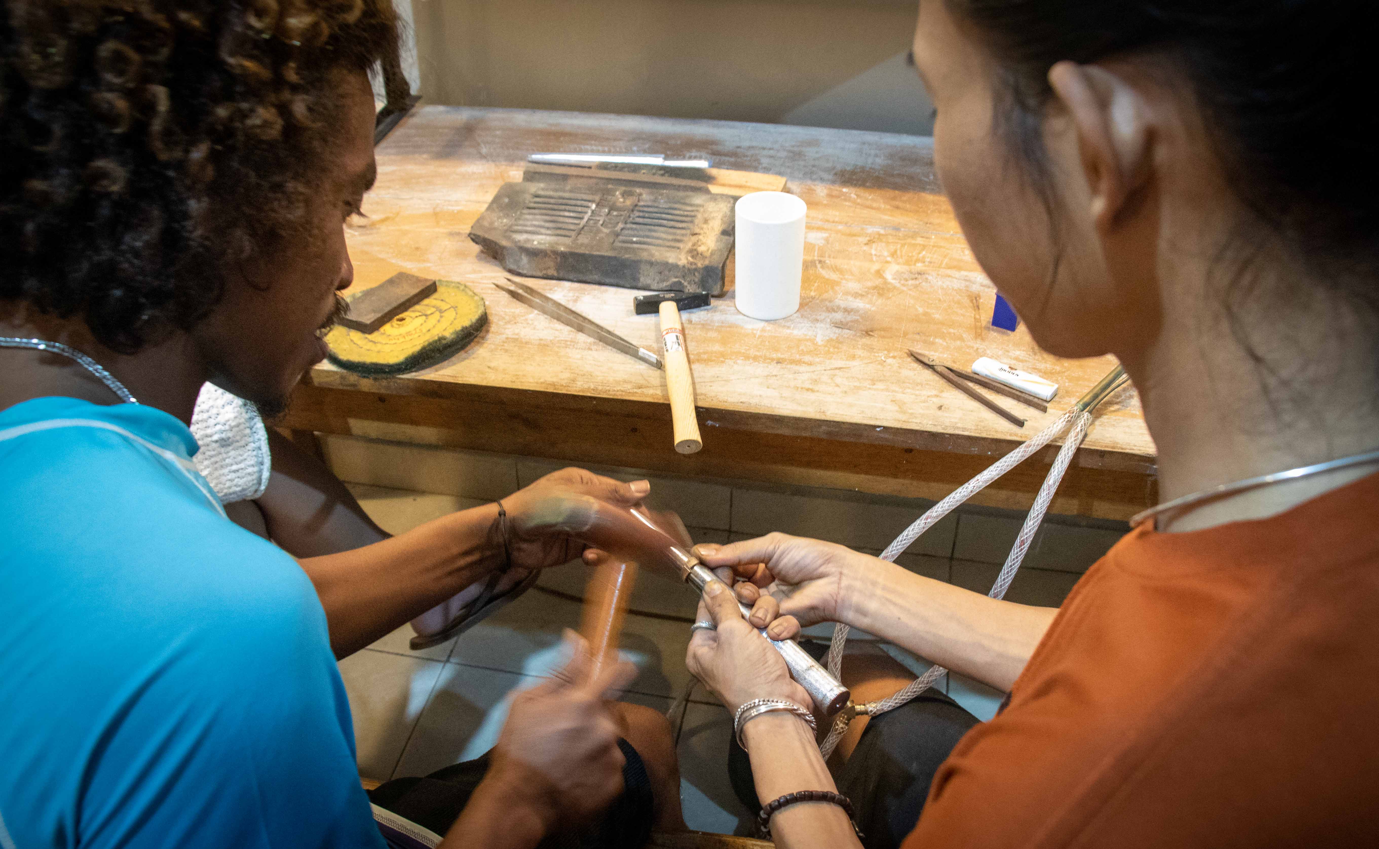 Hands working together at a jewelry-making bench